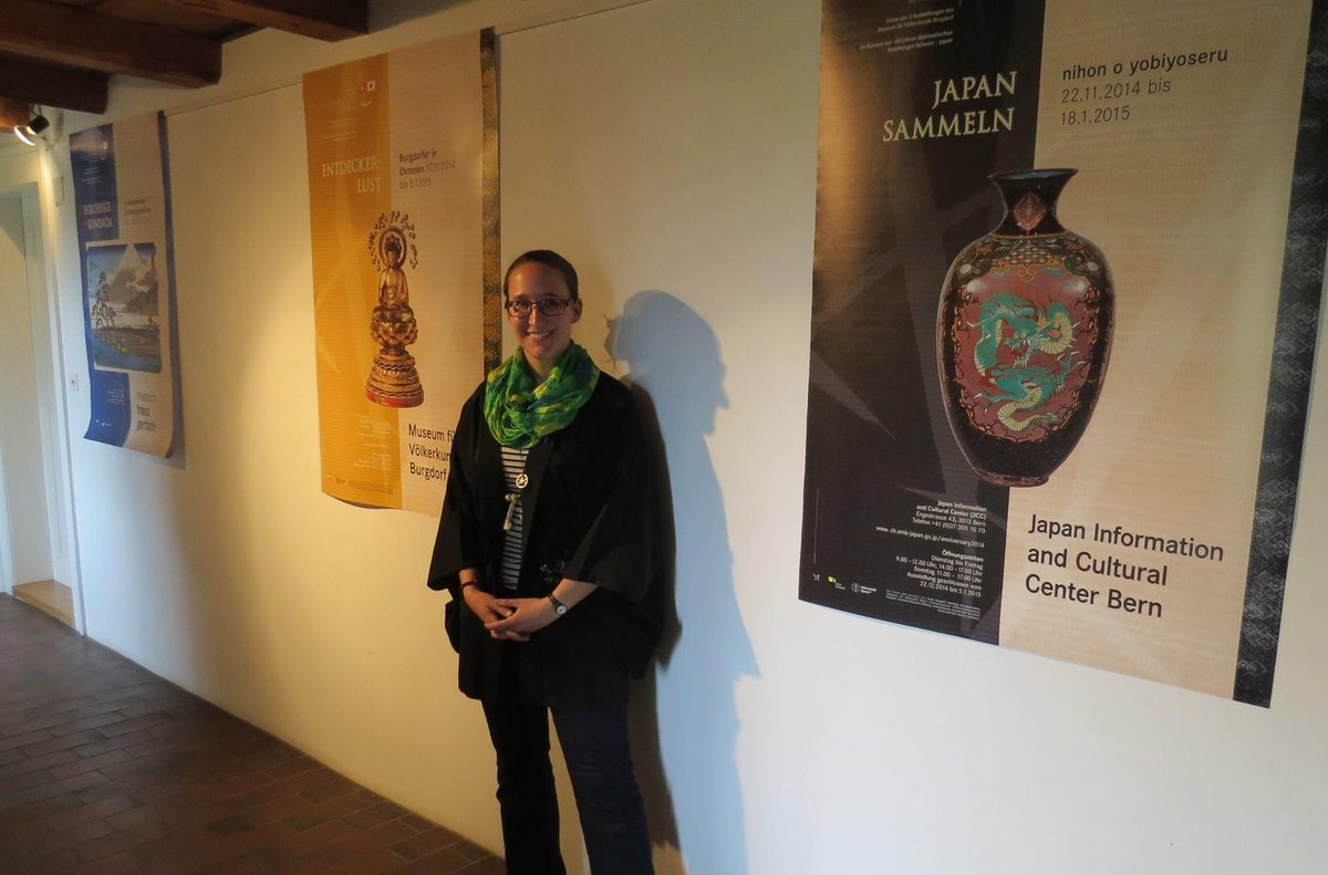 Stephanie Santschi standing between the exhibition posters for Entdeckerlust and Japan Sammeln